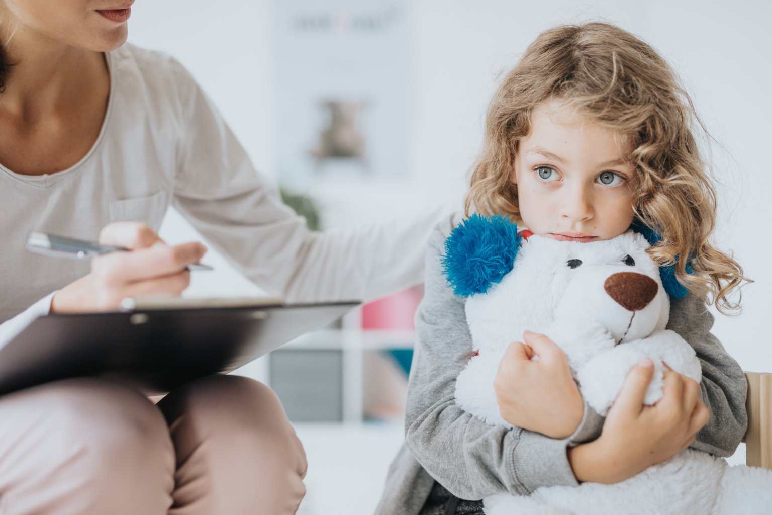 Young sad boy sitting with his teddy bear on a session with therapist