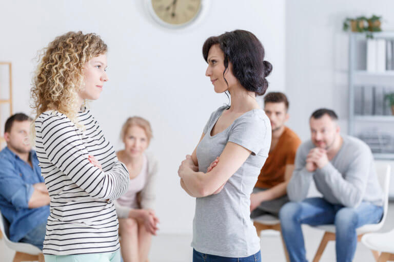 Two happy women making amends during a group psychotherapy meeting